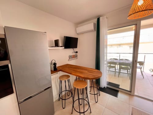 Modern kitchen area in Marina di Bravone apartment with wooden counter, bar stools, and terrace access in Linguizzetta