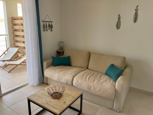 Beige sofa with teal pillows in Marina di Bravone apartment living room, wooden coffee table, coastal decor, beach access