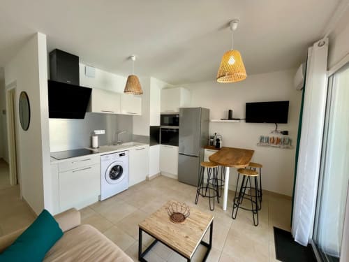 Modern open-plan kitchen and living area at Résidence Marina di Bravone in Linguizzetta with white cabinetry and beachfront