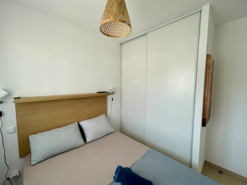 Modern bedroom at Résidence Marina di Bravone with wooden headboard, white pillows, and built-in wardrobe in Linguizzetta