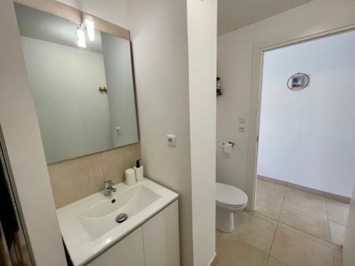 Modern bathroom at Résidence Marina di Bravone with sink, mirror, toilet, and neutral tiling