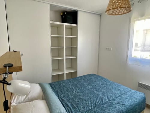 Camera luminosa a Résidence Marina di Bravone con letto blu, scaffali bianchi e vista sul mare a Linguizzetta