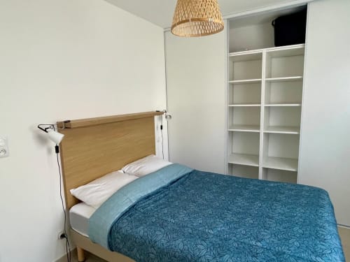Camera moderna presso la Résidence Marina di Bravone con letto in legno, mensole bianche e biancheria teal a Linguizzetta