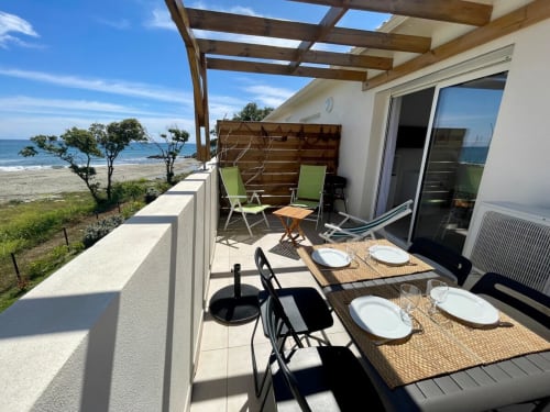 Terrazza di appartamento sul lungomare a Marina di Bravone con tavolo da pranzo, lettini e vista mare a Linguizzetta