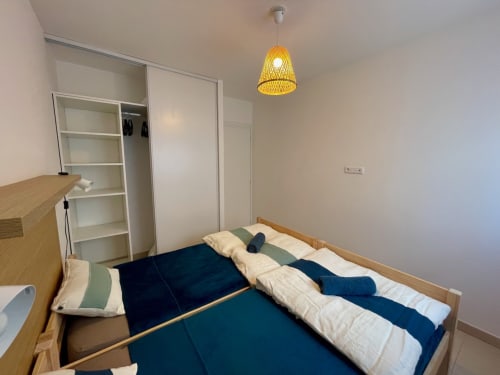 Chambre moderne à la Résidence Marina di Bravone, Linguizzetta avec lit en bois, literie rayée, penderie blanche et suspension