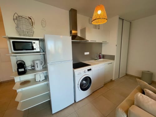 Cuisine moderne de l'appartement à la Résidence Marina di Bravone à Linguizzetta avec appareils, placards blancs et coin repas