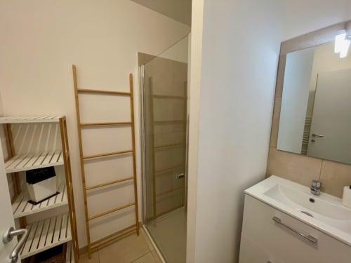 Salle de bain moderne à la Résidence Marina di Bravone avec douche, lavabo, miroir et étagère échelle en bois