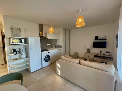 Appartement T3 Marina di Bravone avec cuisine ouverte, canapé crème et luminaires en rotin à Linguizzetta