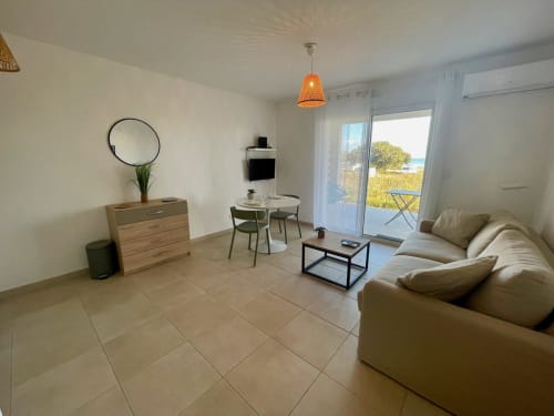 Studio moderne à la Résidence Marina di Bravone avec vue mer, canapé beige, coin repas et balcon panoramique