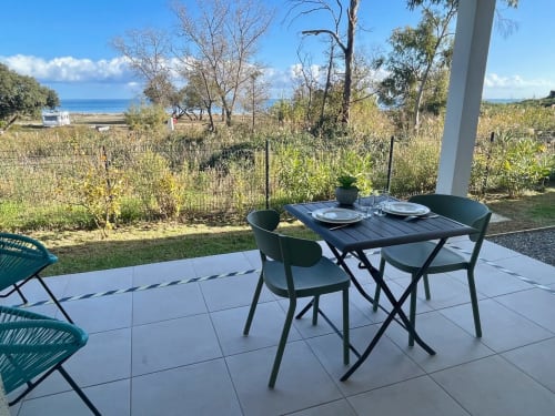 Coin repas en terrasse à la Résidence Marina di Bravone à Linguizzetta avec vue sur la mer et le jardin