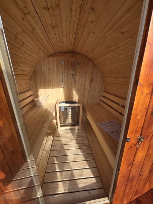 Interior of barrel-shaped sauna at Casa da Ioio villa in Madalena with wooden benches and heater