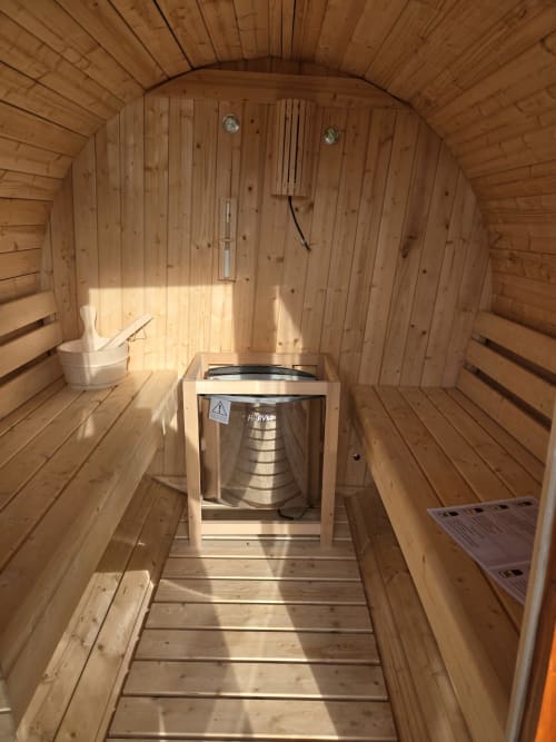 Interior of wooden sauna at Adega da Quinta villa in Madalena with heater, benches, and bucket