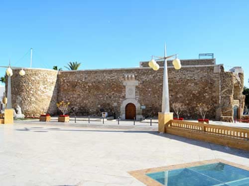 La Llar bnb en Carboneras: alojamiento con fachada de fortaleza de piedra, linternas y piscina en patio