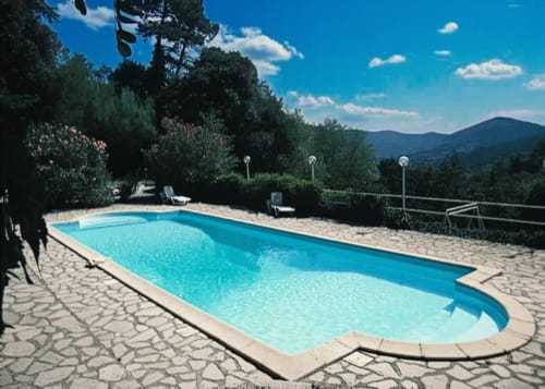 Piscine aux eaux cristallines du Domaine de Cabrières à Saint-Jean-du-Gard avec vue sur les montagnes et transats