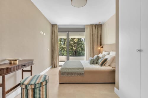 Nowoczesna sypialnia w apartamencie HomyMarbella w Elvirii z widokiem na ogród, beżowym wyposażeniem i dostępem na balkon
