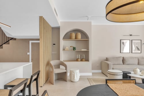 Nowoczesny salon w HomyMarbella Elviria z beżową sofą, drewnianymi półkami i współczesnym wyposażeniem