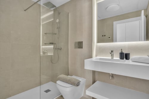 Nowoczesna łazienka w apartamencie HomyMarbella SeaView w Elvirii z prysznicem, toaletą i oświetlonym lustrem