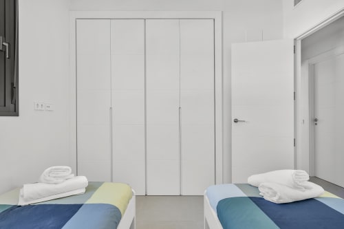 Sypialnia z łóżkiem małżeńskim, białą pościelą i kolorowym zdobieniem w apartamencie HomyMarbella w Elvirie, koło pola golfowego Calanova