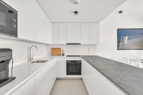 Nowoczesna biała kuchnia z ciemnymi blatami w apartamencie HomyMarbella SeaView, Elviria, Hiszpania