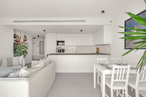 Nowoczesny apartament typu open space w Marbelli z białą kuchnią, jadalnią i salonem z widokiem na morze