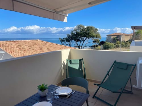 Balcone dello studio a Marina di Bravone con vista mare, lettini verdi, tavolo da pranzo, Linguizzetta Corsica