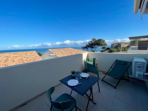 Terrazza dello studio presso la Résidence Marina di Bravone con vista mare, tavolo da pranzo, lettino e paesaggio costiero corso