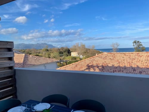 Vista dal balcone della Résidence Marina di Bravone: mare, montagne, tetti in terracotta e zona pranzo