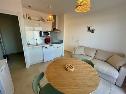 Moderno appartamento a Résidence Marina di Bravone con cucina open-plan, tavolo da pranzo, divano e arredi in legno