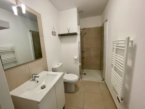 Salle de bain moderne à la Résidence Marina di Bravone avec lavabo, toilettes, douche, sèche-serviettes chauffant et miroir