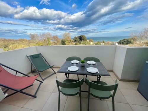 Terrasse avec table à manger, vue sur mer et transats à Marina di Bravone, Linguizzetta