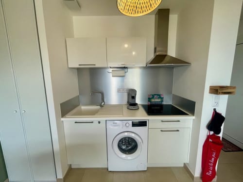 Petite kitchenette à l'appartement Marina di Bravone avec lave-linge, plaque de cuisson, évier et dosseret en acier inoxydable