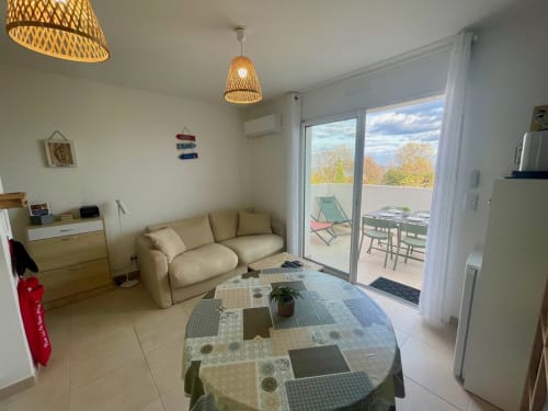 Lumineux séjour à Marina di Bravone avec canapé beige, table ronde et accès à terrasse vue mer à Linguizzetta