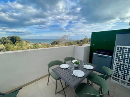 Terrasse en bord de mer de la Résidence Marina di Bravone avec table à manger, vue sur la mer et cuisine extérieure moderne à Linguizzetta