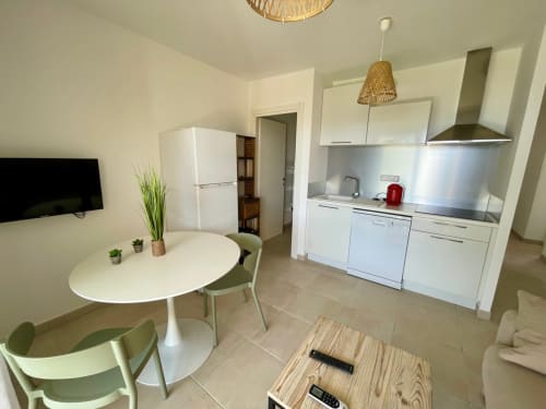 Cucina e zona pranzo moderna a Résidence Marina di Bravone a Linguizzetta con mobili bianchi e tavolo rotondo