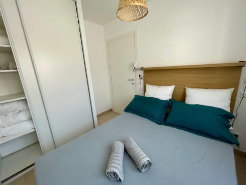 Camera moderna a Résidence Marina di Bravone a Linguizzetta con letto in legno, biancheria turchese e vista mare