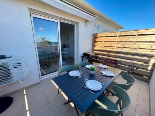 Terrazza fronte mare di Résidence Marina di Bravone con tavolo da pranzo, vista sul mare e schermo di legno per la privacy