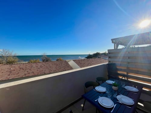 Balcone fronte mare a Marina di Bravone con vista sul mare, tavolo apparecchiato e tetti costieri a Linguizzetta