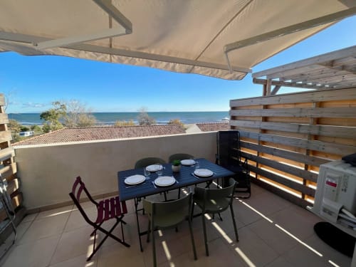 Terrazza fronte mare di Résidence Marina di Bravone con tavolo da pranzo, vista sul mare e zona relax ombreggiata