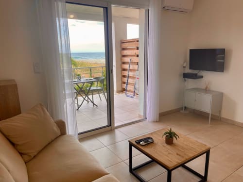 Monolocale con vista mare presso Résidence Marina di Bravone, con terrazza, divano beige, TV e vista oceano