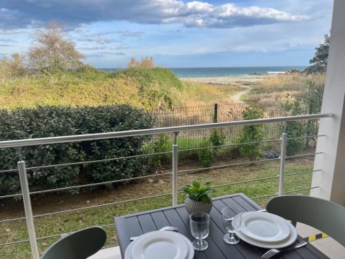 Cena affacciata sul mare a Résidence Marina di Bravone, Corsica. Terrazza costiera con tavolo apparecchiato, vista sul mare e vegetazione costiera.
