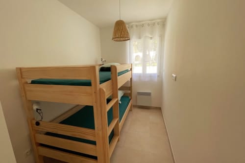 Lits superposés aux matelas verts dans une chambre lumineuse de la Résidence Marina di Bravone, Linguizzetta