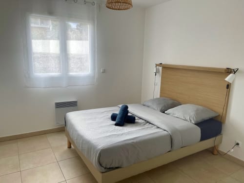 Chambre lumineuse à la Résidence Marina di Bravone avec lit en bois, literie blanche et vue sur la mer à Linguizzetta