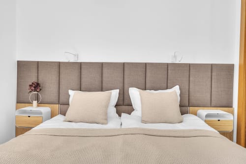 Elegante dormitorio en la casa rural HomyMarbella con cabecero acolchado, sábanas beige y mesillas de madera con flores