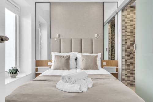 Dormitorio moderno en la casa HomyMarbella de Marbella con cabecero a rayas, ropa de cama blanca, toallas enrolladas y baño privado