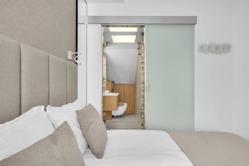 Dormitorio moderno en casita HomyMarbella, Marbella, con acceso a baño privado, cabecero beige y ropa de cama blanca