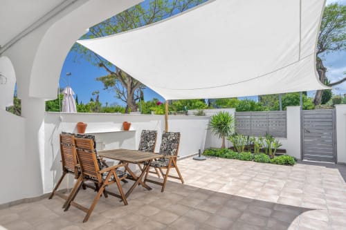 Patio moderno con comedor, vela de sombrilla blanca y vistas al jardín de la casa HomyMarbella en Elviria, Marbella