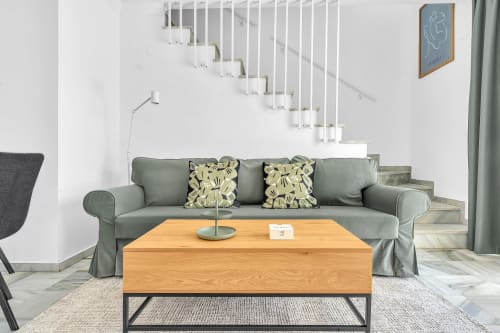 Sala de estar moderna en cottage HomyMarbella con sofá gris, mesa de café de madera y escalera en complejo Elviria