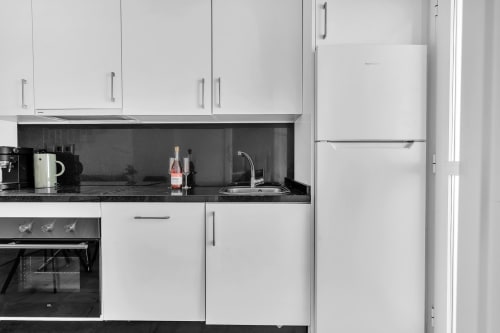 Moderna cocina blanca con encimera negra, electrodomésticos de acero inoxidable y fregadero en la casa rural HomyMarbella de Marbella