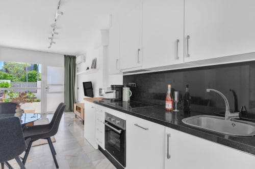 Cocina moderna con encimeras negras y muebles blancos en la casita HomyMarbella, Elviria