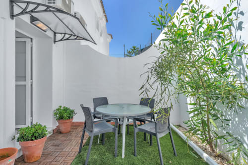 Patio privado de la casita HomyMarbella en Elvíria con mesa de comedor, sillas, plantas en macetas y paredes blancas bajo cielo azul